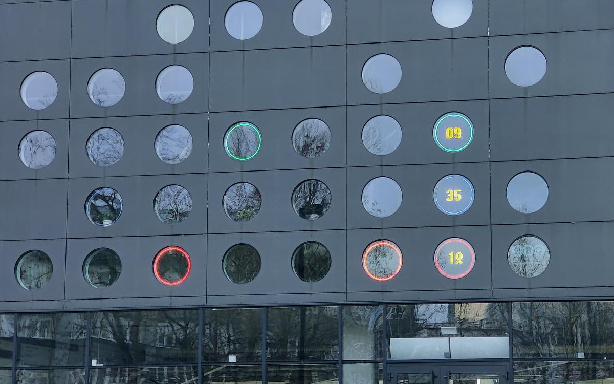 Zdjęcie budynku z oknami przerobionymi na zegar binarny. Wskazuje godzinę 9:35:19.